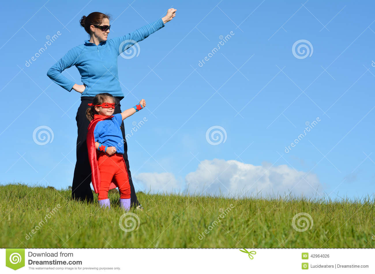 Superhero Mother And Daughter Against Dramatic Blue Sky Background    