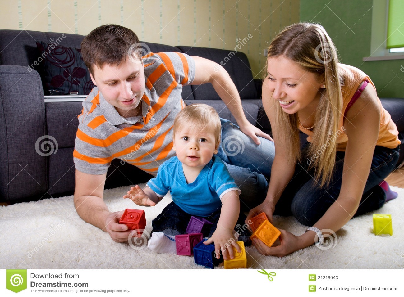 Family With Baby Boy Sitting On Floor At Home And Playing Together