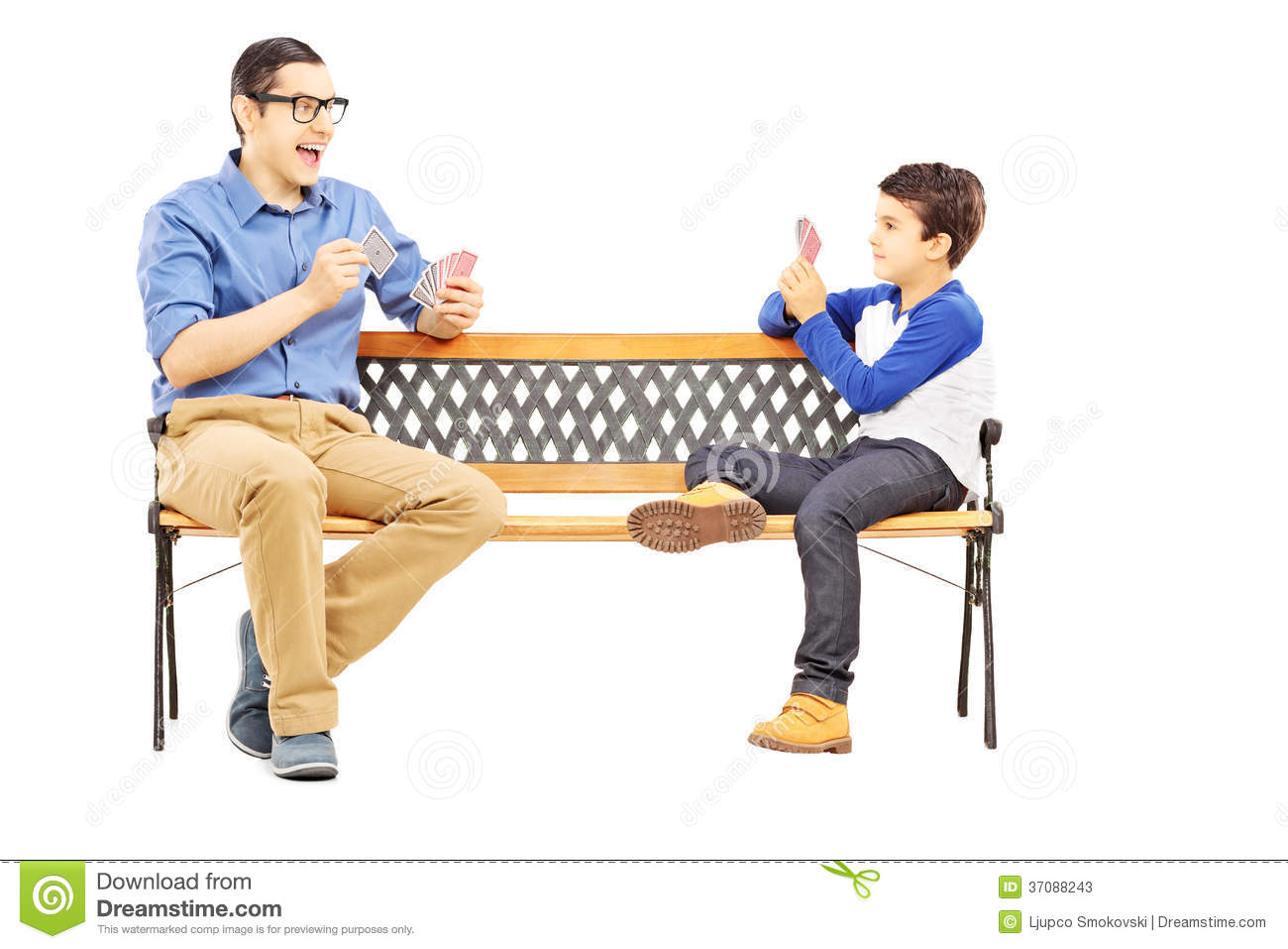 Young Boy Playing Cards With His Older Cousin Seated On Bench Isolated