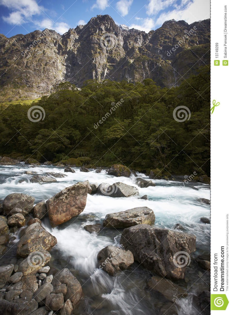 Mountain River Skipping Over The Rocks With Forest And Mountains In