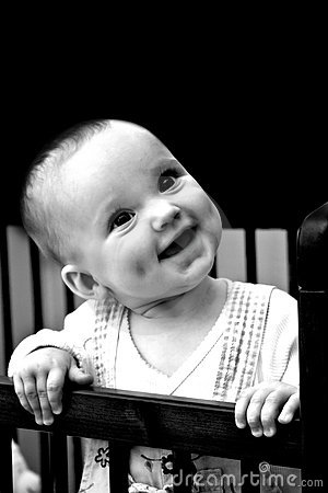 Happy Laughing Cute Baby With Dimples Stands In Baby Bed  Black And