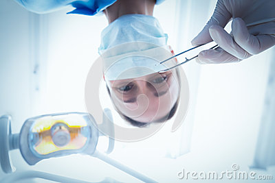 Angle Portrait Of Female Dentist In Surgical Mask Holding Dental Tool