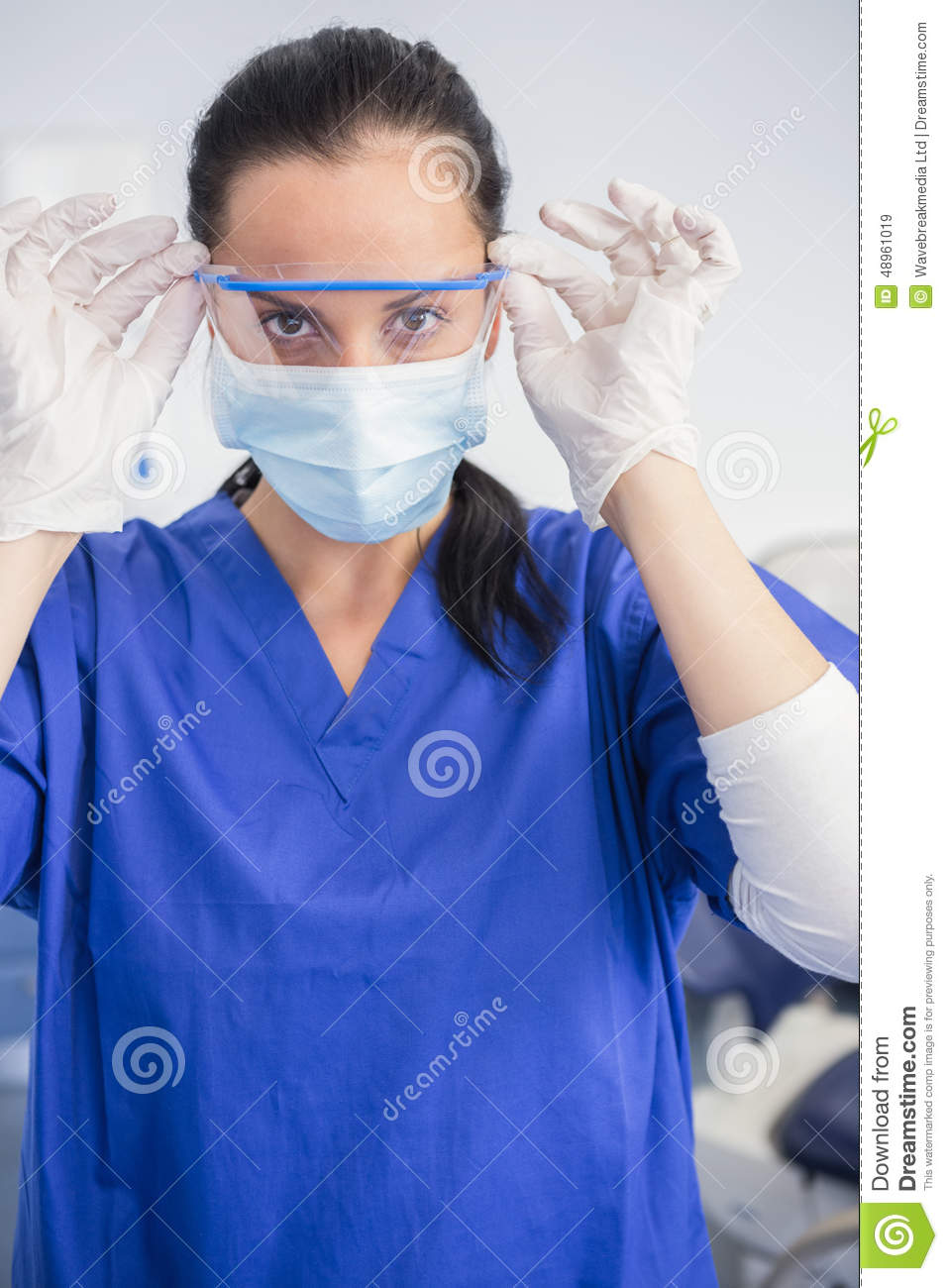 Dentist With Surgical Mask Putting On Her Safety Glasses Stock Photo