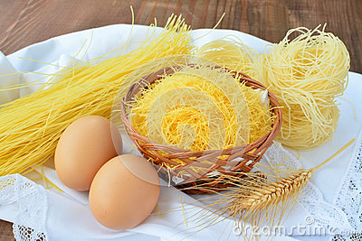Assortment Of Egg Noodles And Two Eggs On White Cloth Over Wooden