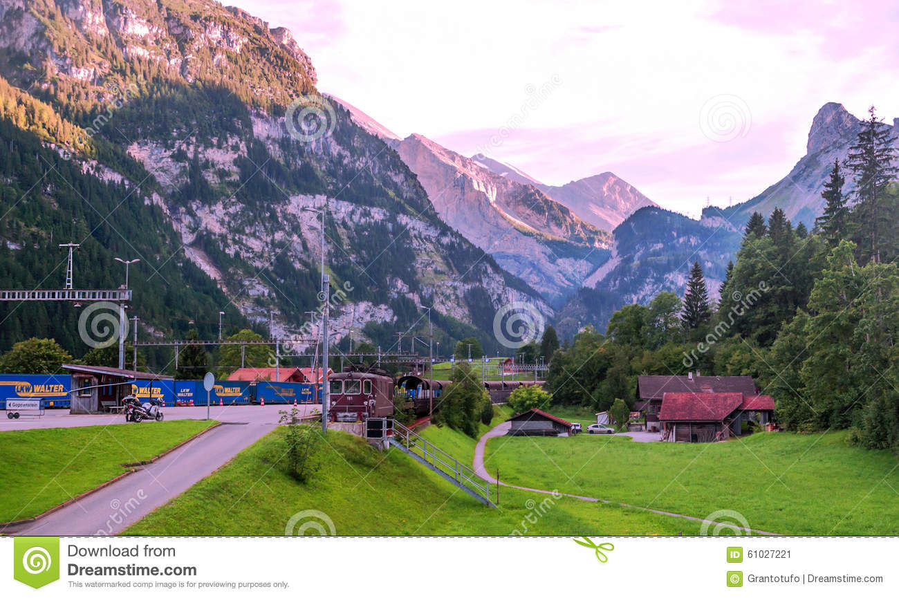 Road With Cars With Wooden Houses In Switzerland  Alpine Mountains In