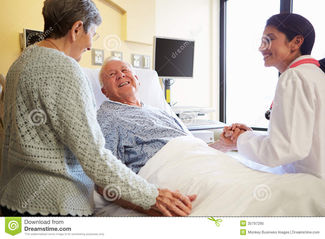 Female Doctor Talking To Senior Couple In Hospital Room Royalty Free