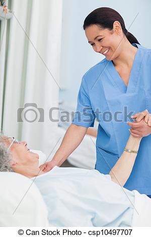 Stock Photography Of Nurse Smiling To A Patient While Holding Her Hand    