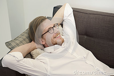 Young Red Haired Man Lying On Couch And Looks Happy