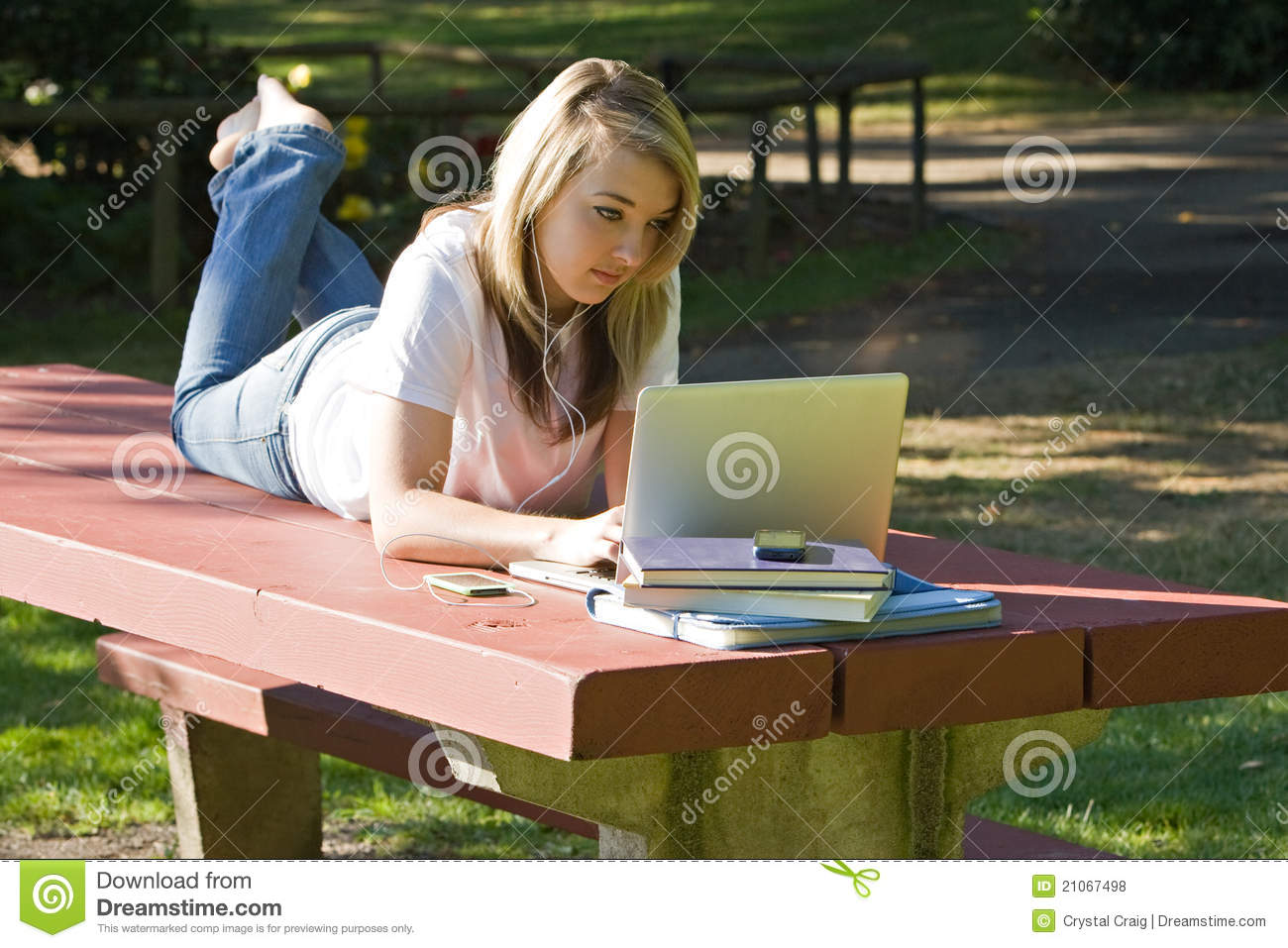 College Age Student Using Laptop Listening To Electronic Device    
