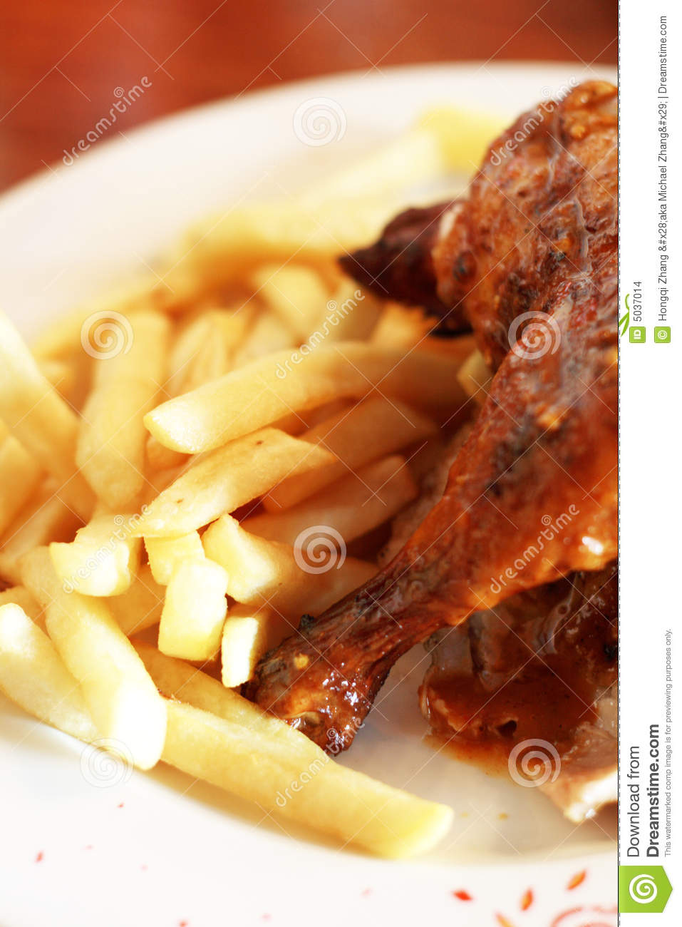 Half Grilled Chicken And Some Deep Fried Chips On A Plate
