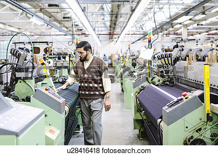 Male Factory Worker Monitoring Weaving Machine Quality In Woollen Mill