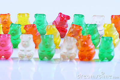 Gummy Bears Lined Up In A Row On Reflective White Material  Red Gummy    
