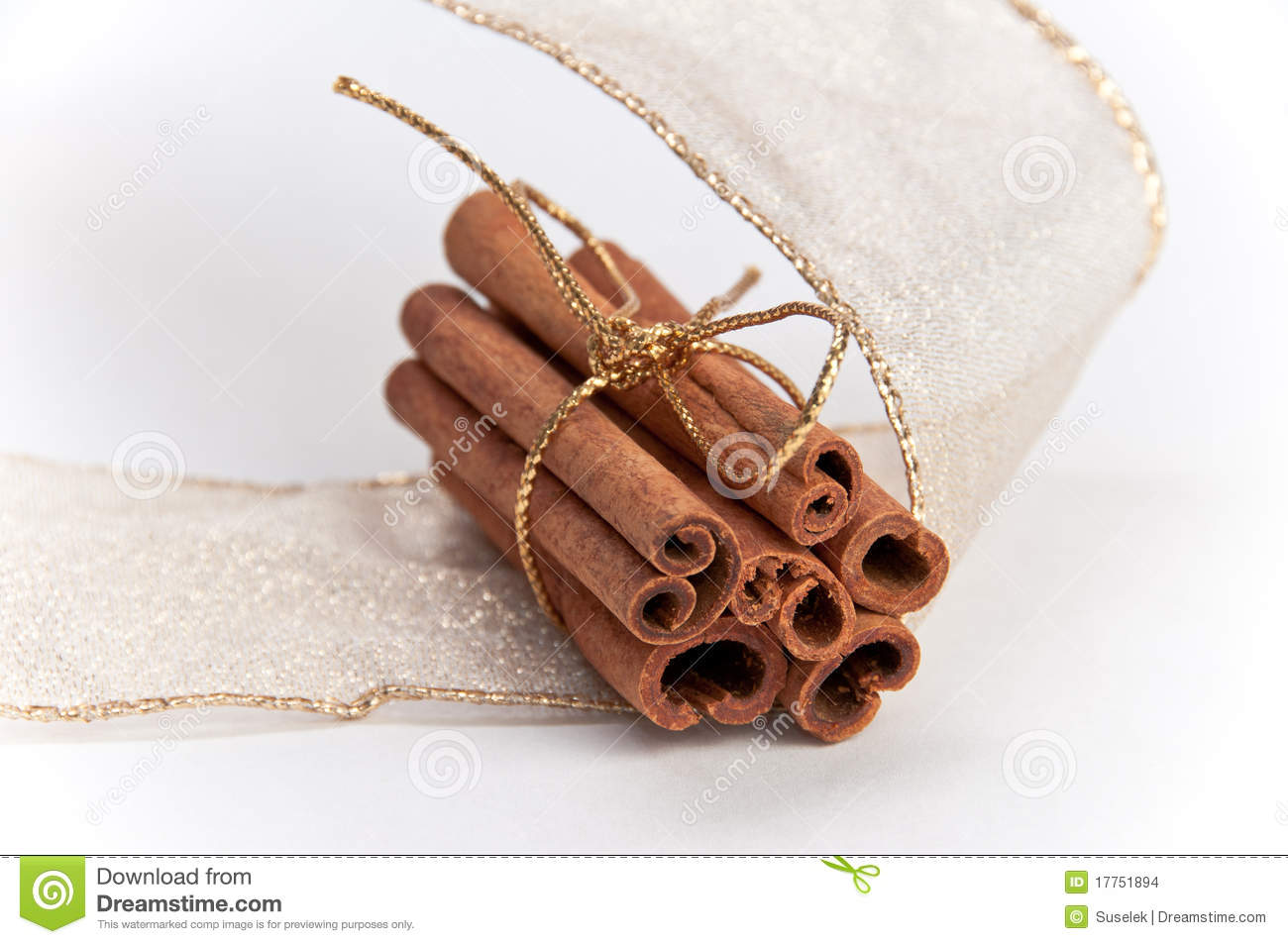 Stack Of Cinnamon Sticks Tied In Gold Ribbon And Decorated With Gold