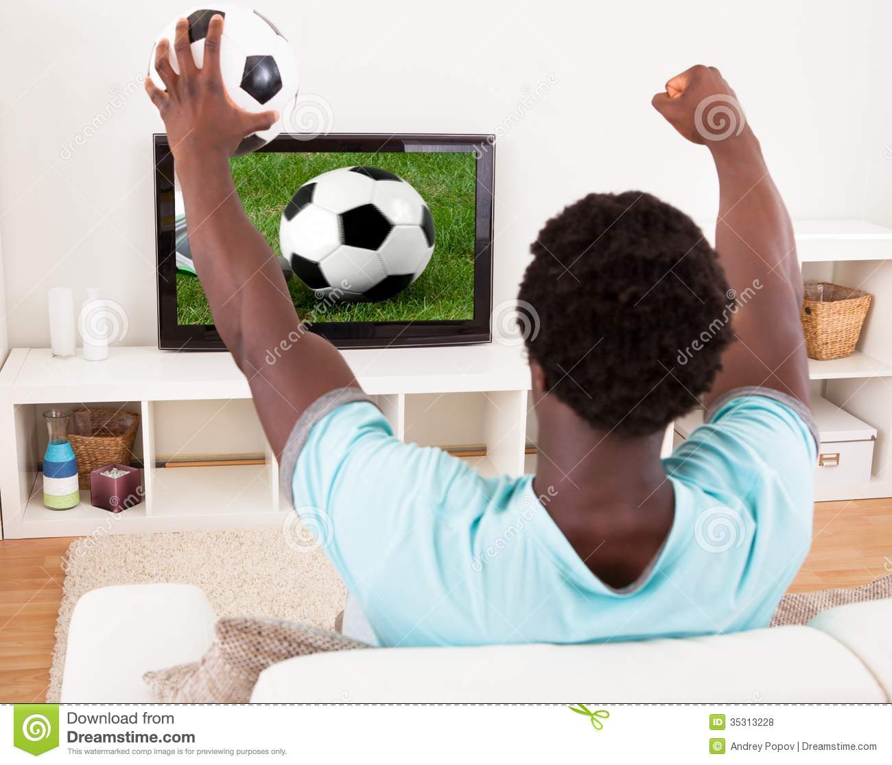     Stock Photos  African Young Man Watching Television Holding Football