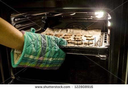 Taking Baked Cookies Out Of The Oven With Kitchen Gloves  Stock Photo