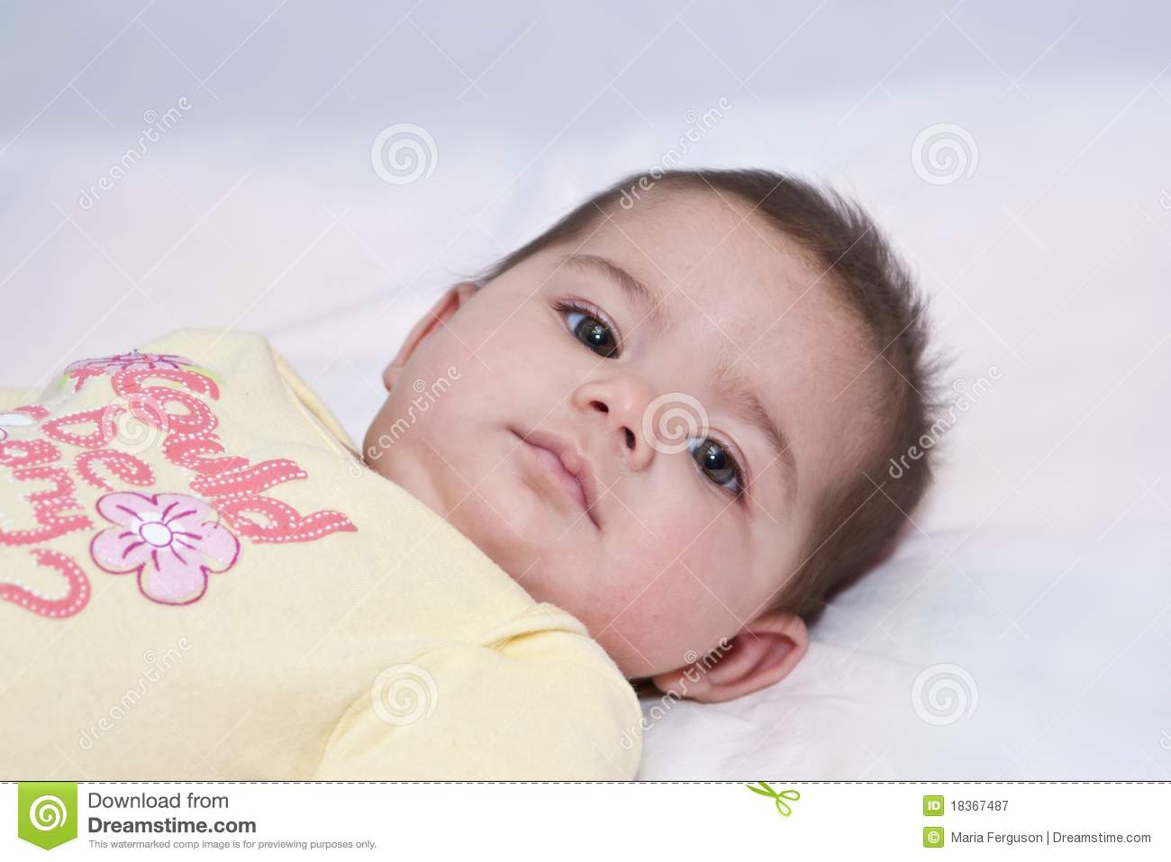 Close Up Of Baby Girl With Dark Hair Big Dark Eyes Looking Intensely 