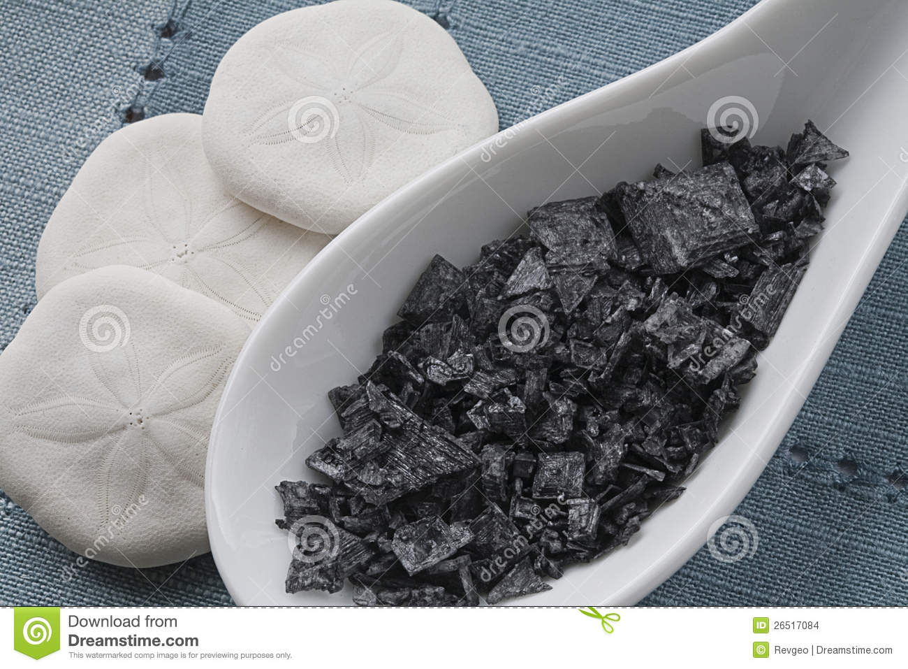 Black Flaked Sea Salt On White Tasting Spoons With Three Sand Dollars    