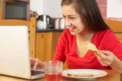 Teenage Girl Using Laptop Whilst Eating Breakfast Royalty Free Stock