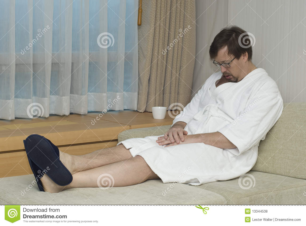 Man Wearing White Robe Slippers And Glasses Has Fallen Asleep While