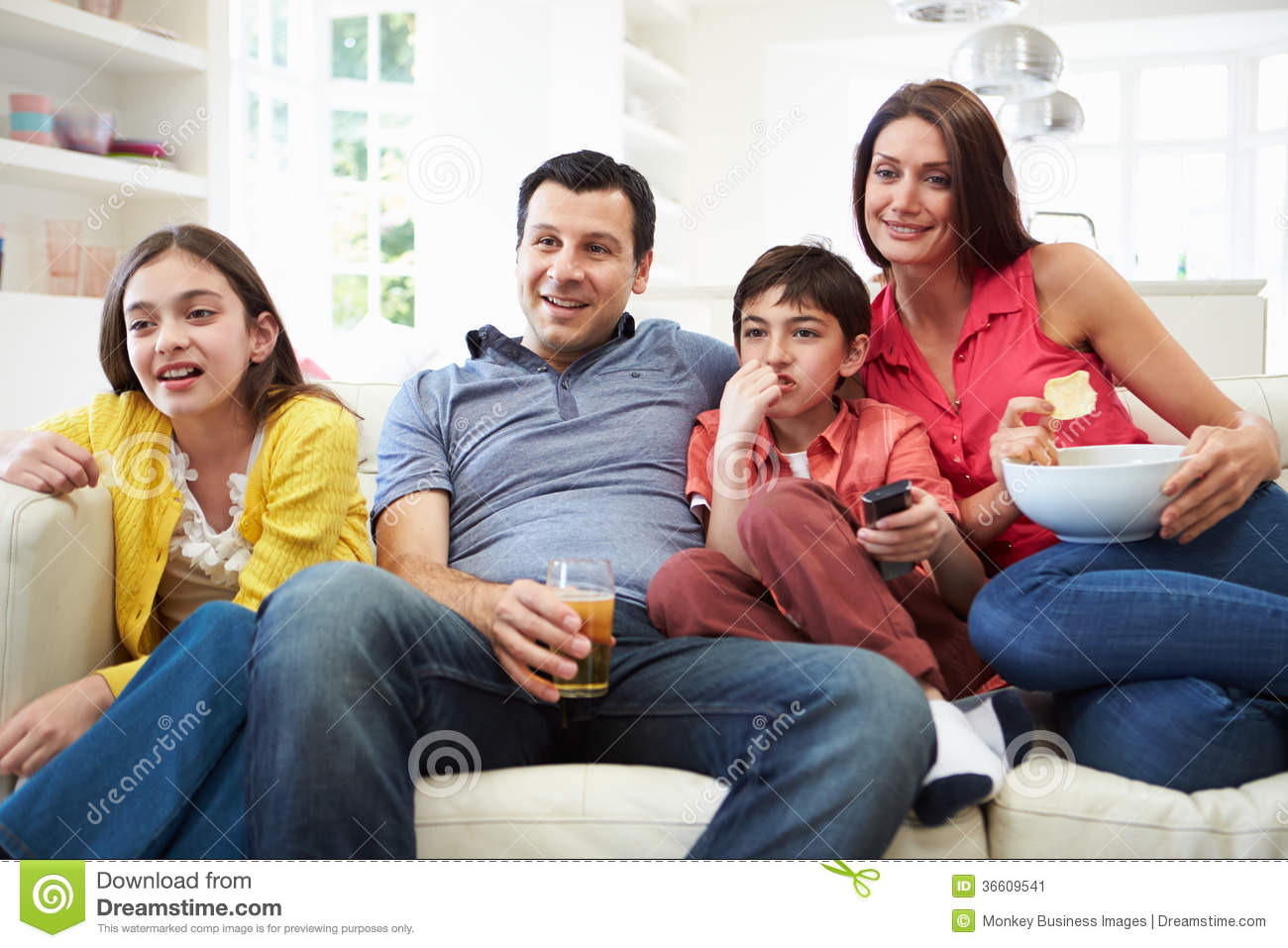 Hispanic Family Sitting On Sofa Watching Tv Together Smiling Away From