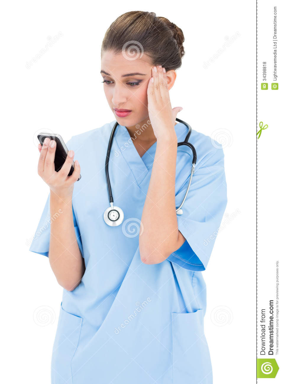 Puzzled Brown Haired Nurse In Blue Scrubs Using A Mobile Phone Royalty    