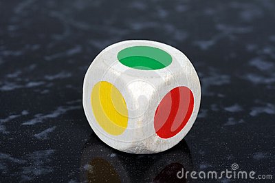 Standard Six Sided Die With Coloured Spots Against A Grey Background