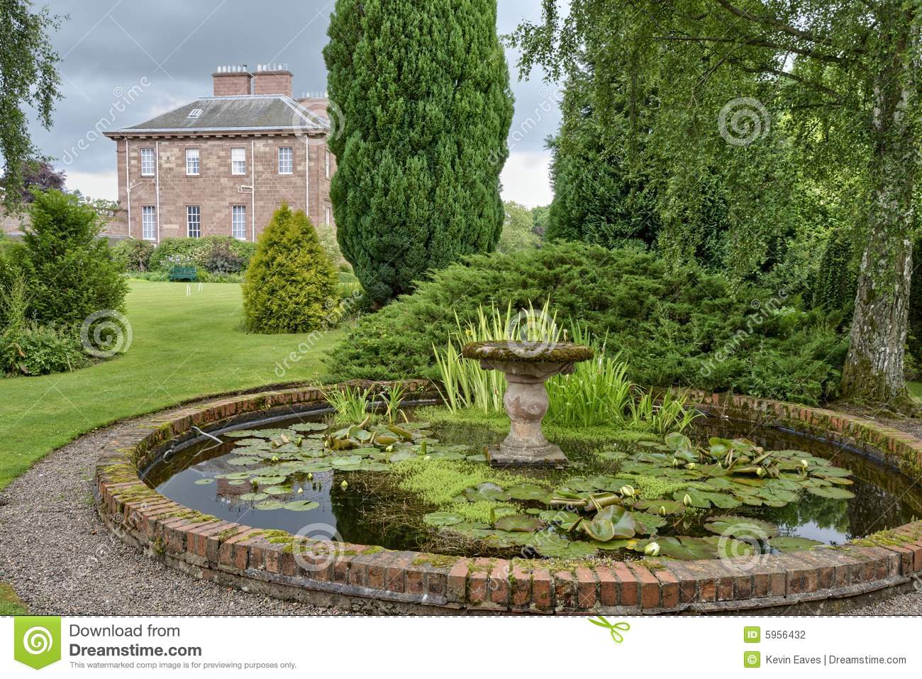 An Ornamental Pond In A Country Estate Garden With A Large House In    