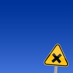 Yellow Three Cornered Road Sign With Cross Over Blue Sky