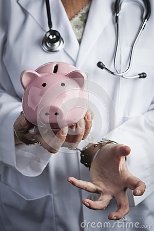 Female Doctor Or Nurse In Handcuffs Holding Piggy Bank Wearing Lab