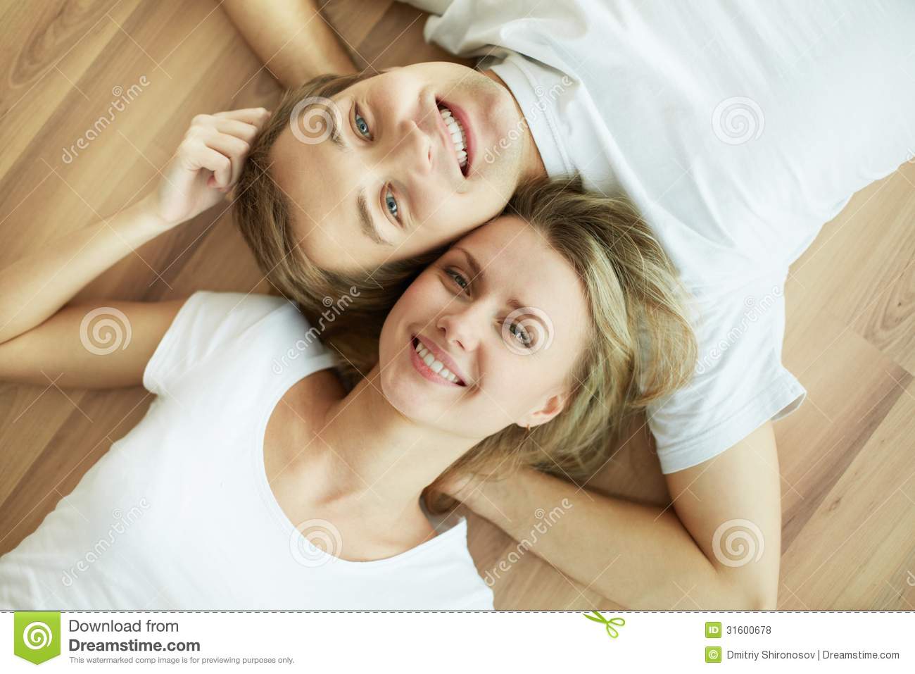 Above Angle Of Young Couple Lying On The Floor And Looking At Camera 