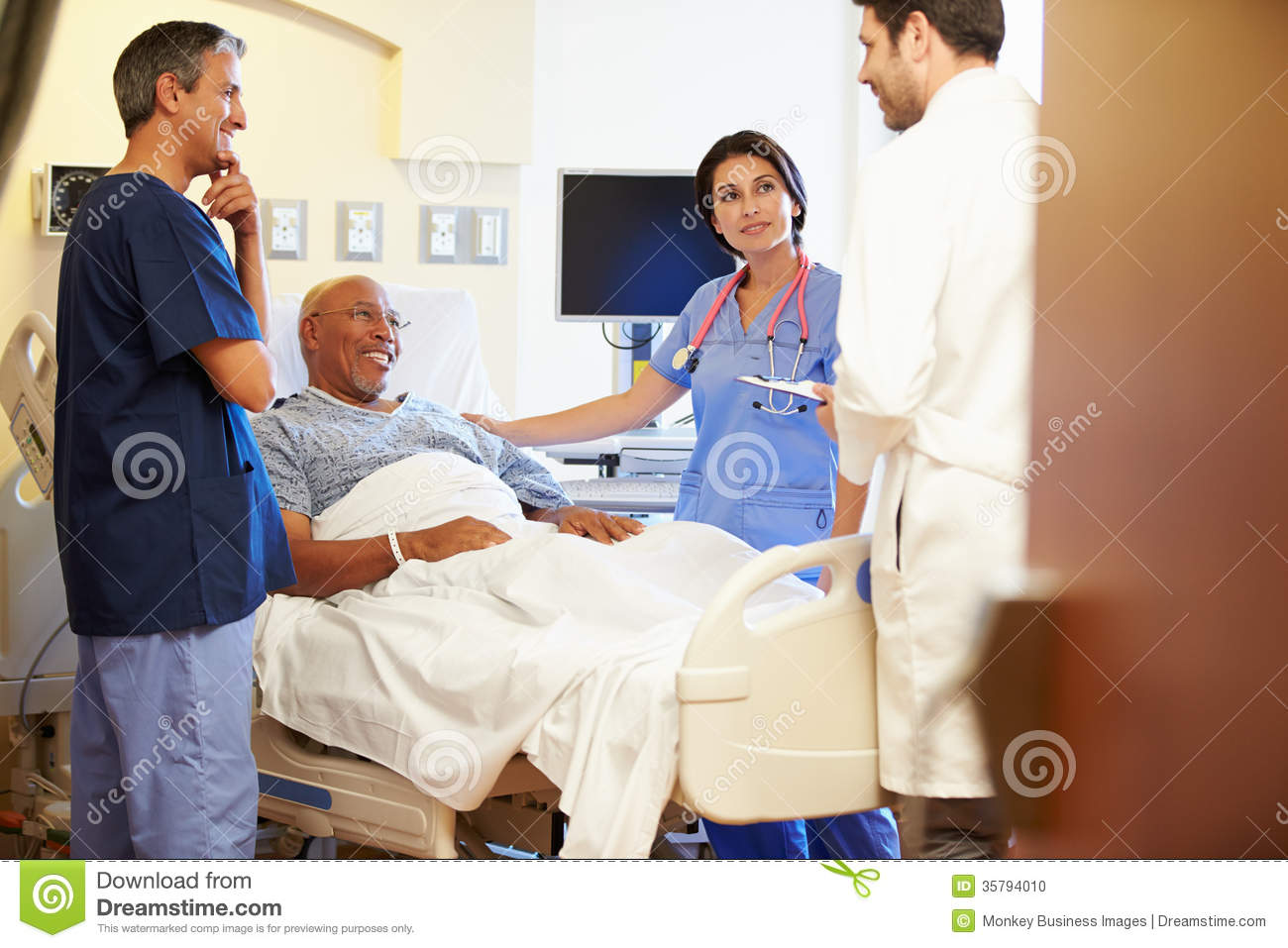 Medical Team Meeting With Senior Man In Hospital Room Looking At Each
