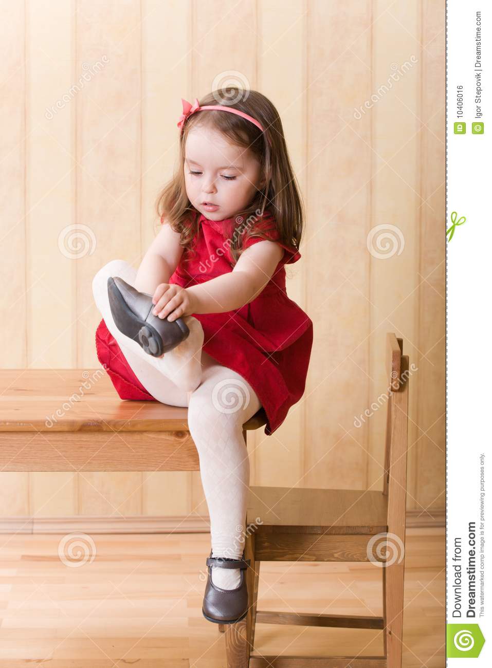 Girl Sitting On Table And Put On One S Shoes Royalty Free Stock Image