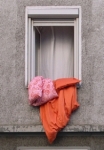 Bright Orange Duvet And Two Pillows Hanging Out Of Window In Concrete