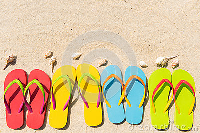 Four Pairs Of Flip Flops In A Row On Beach