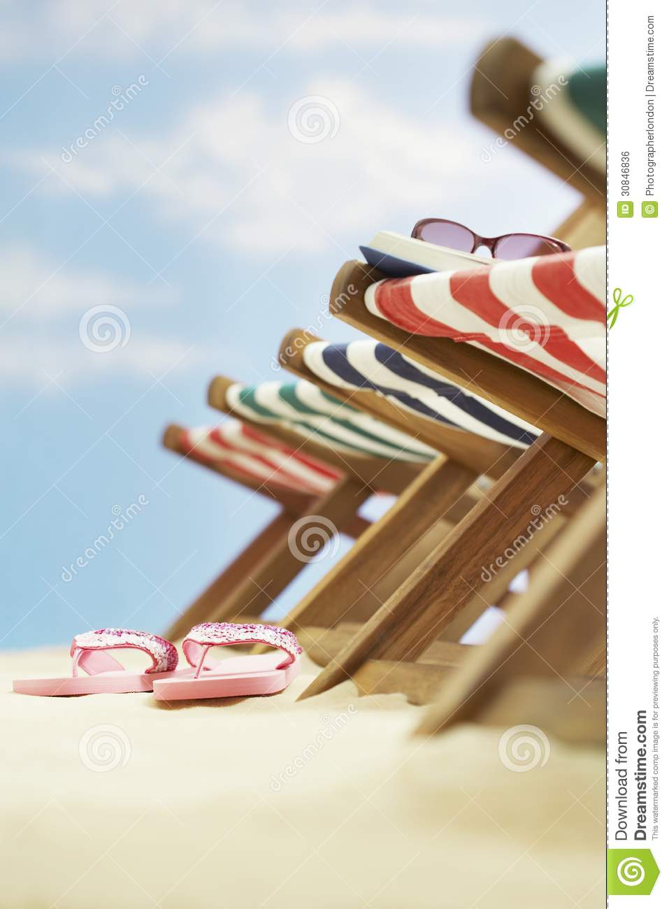 Row Of Deck Chairs On Beach Focus On Flip Flops On Ground Royalty Free