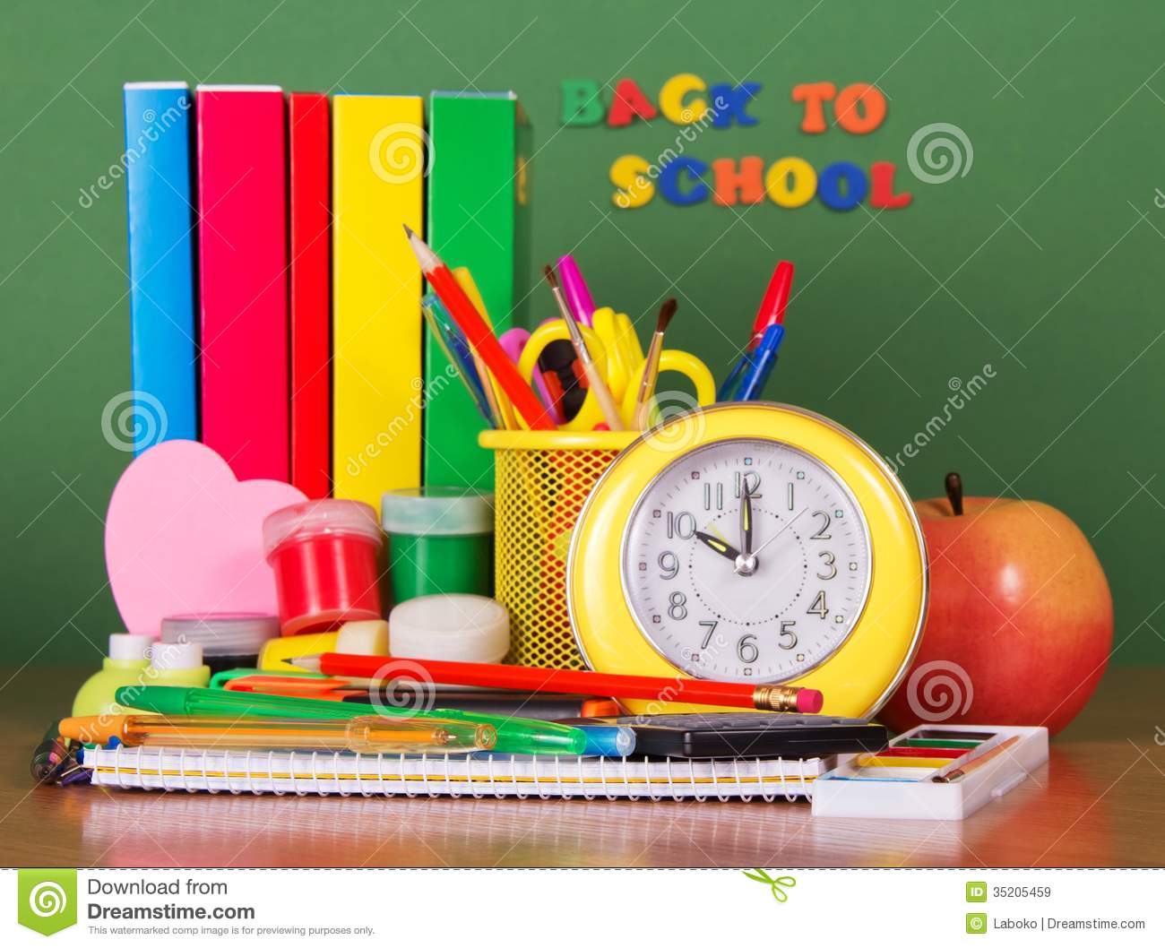 Pile Of Books Set Of Writing Materials An Alarm Clock And Apple On A