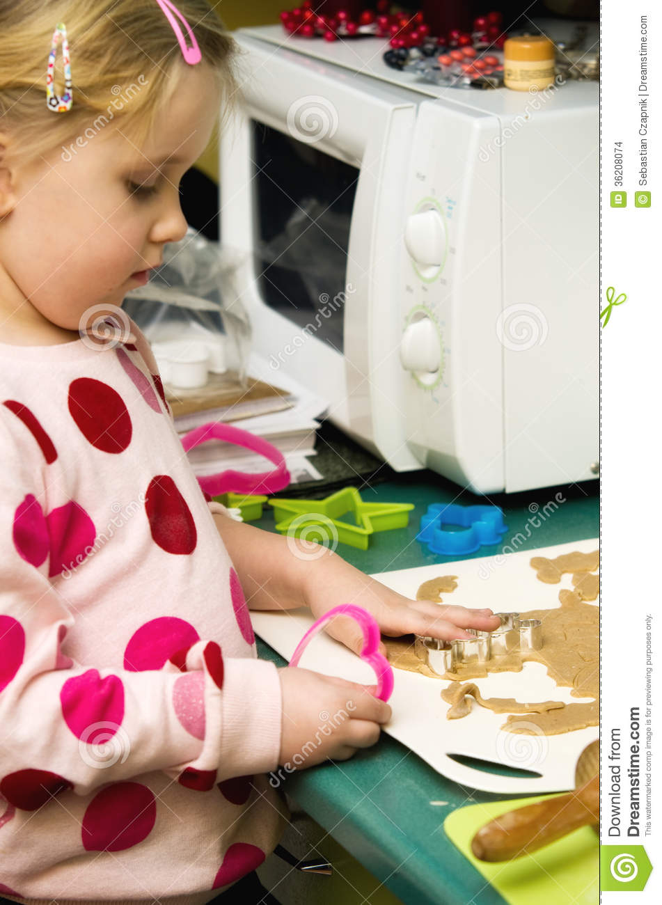Cute Little Girl Sitting At Kitchen Table Making And Decorating    