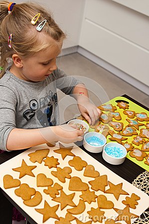 Young Child Putting Sprinkles On Christmas Cookie Cutouts In Shapes Of    