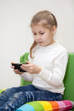Pretty Caucasian Girl Playing Game On Cellphone Sitting Indoor Stock