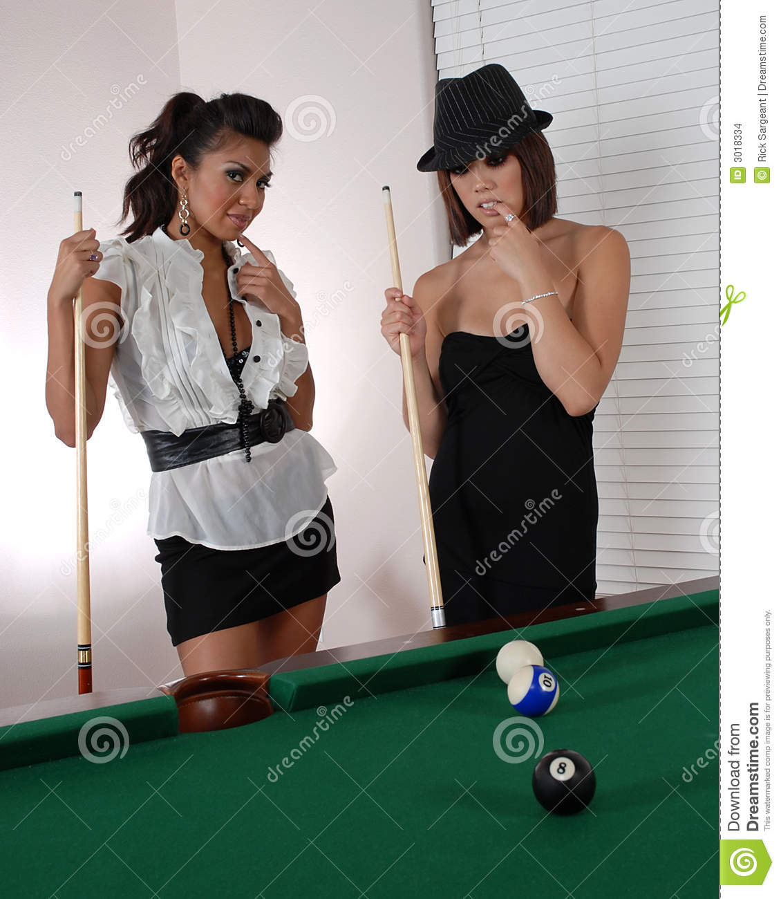 Two Women Holding Pool Sticks Or Cues Next To A Pool Table 