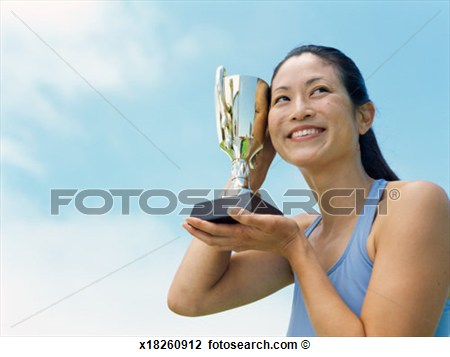 Low Angle View Of A Female Athlete Holding A Trophy View Large Photo