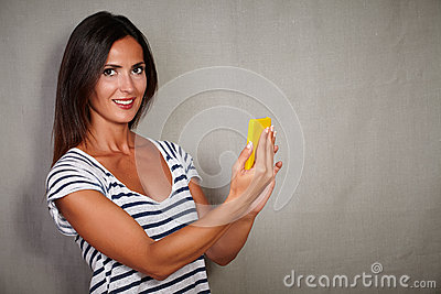 Charismatic Young Lady Holding Mobile Phone While Looking At Camera    