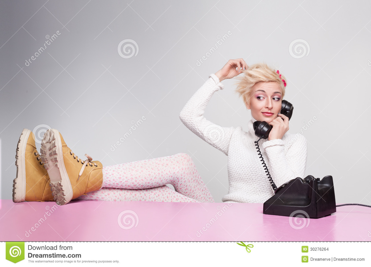 Young Lady Speaking On The Phone While Her Legs On The Desk