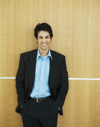 Latino Or Hispanic Businessman Smiling And Standing Against A Wood
