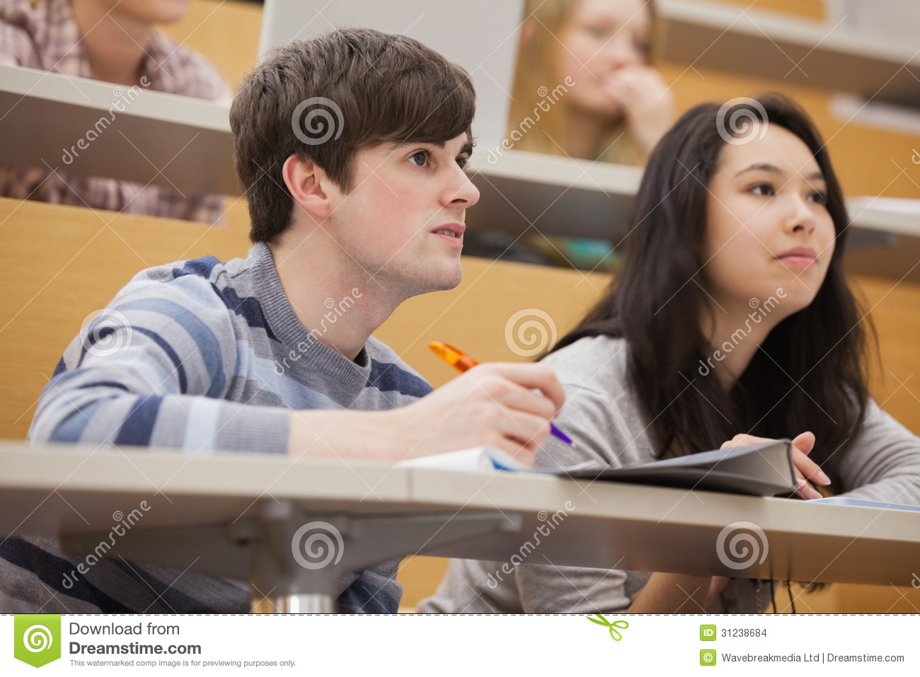 Students Sitting In A Lecture Hall While Studying And Listening To The