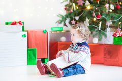 Toddler Girl Reading Book Under Christmas Tree Stock Photography