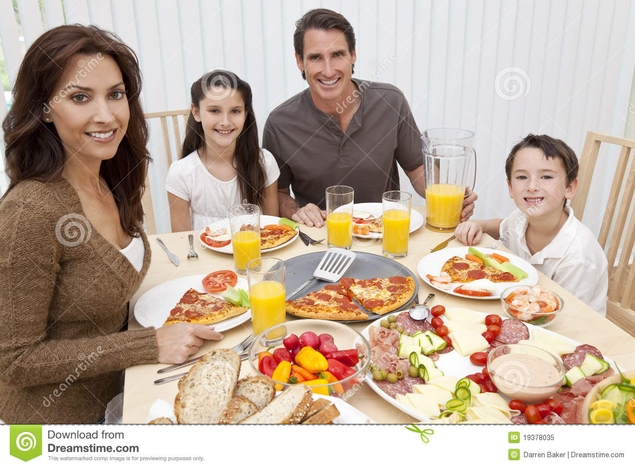 Family Of Mother Father Son And Daughter Eating Salad And Pizza At A