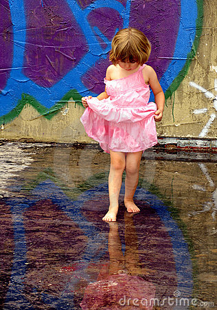 Little Girl Playing In Rain Puddles With Reflections