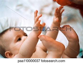 Picture Of Baby Lying On Back Reaching Up With Hands And Feet Close