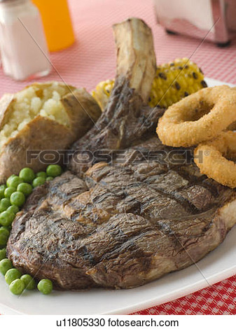 Ribeye Steak On The Bone With Baked Potato Peas Onion Rings And Corn    